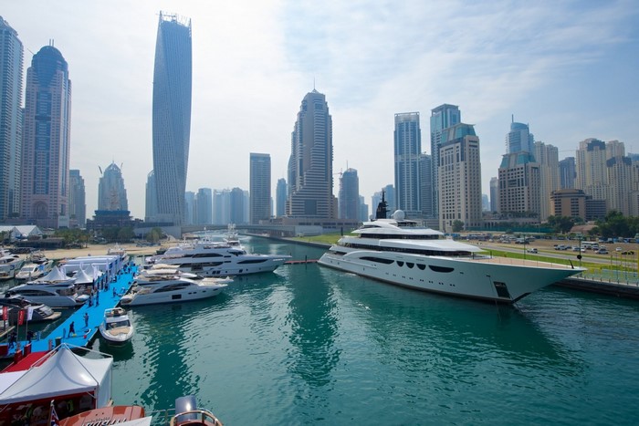 Luxury yachts docked in a modern city harbor with skyscrapers