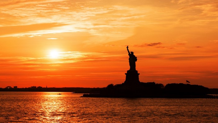 Statue of Liberty silhouette at sunset over the ocean