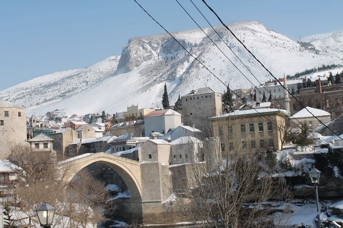 Mostar Old Bridge in winter with snow-covered mountains