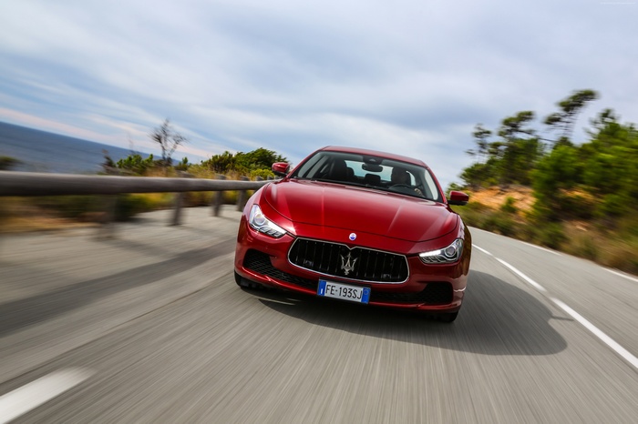 Red Maserati Ghibli S Q4 driving on a coastal road