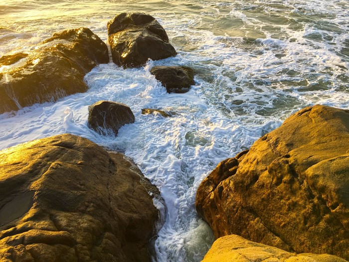 Waves crashing on rocks at sunset