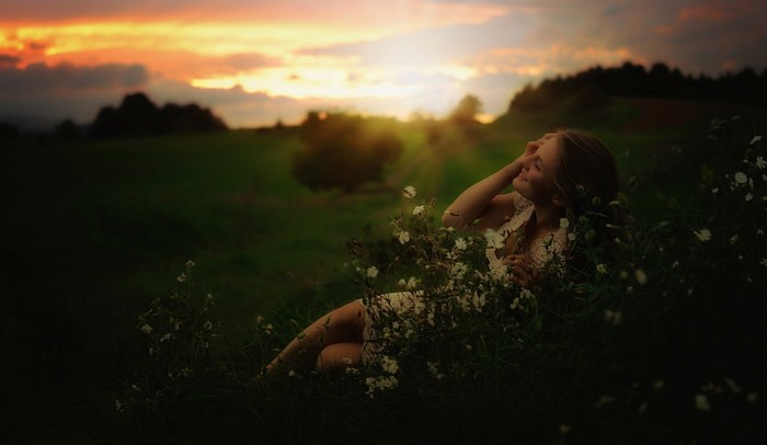 Woman lying in grass at sunset