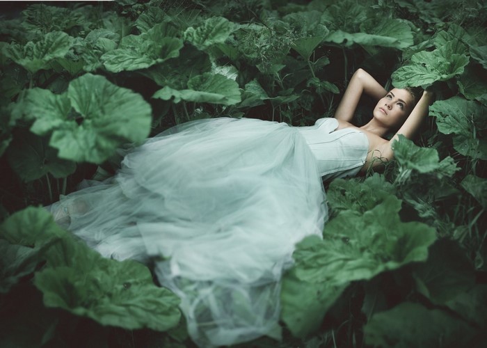 Woman in white dress lying in green plants
