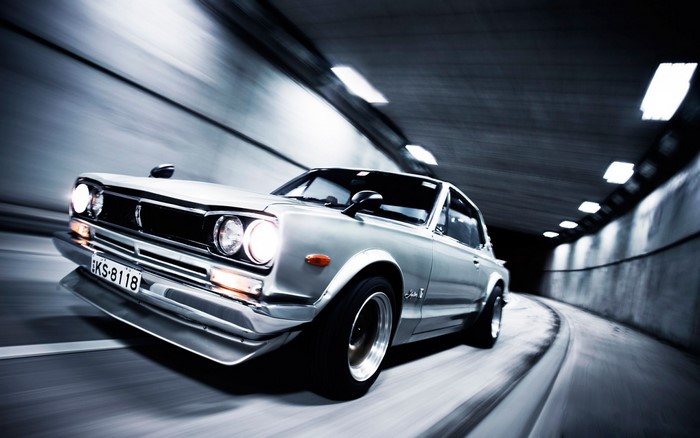 Silver classic Nissan Skyline GT-R driving through a tunnel