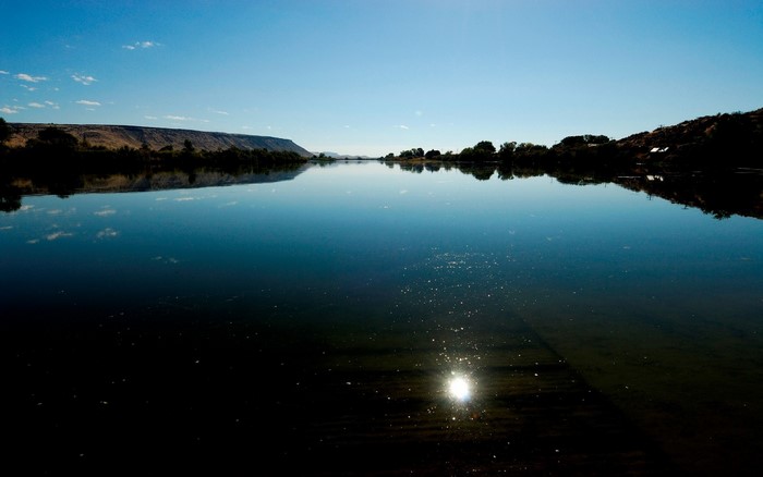 Calm lake reflecting a clear blue sky and distant hills