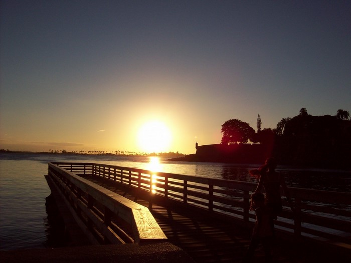 Sunset over the ocean with a pier and people