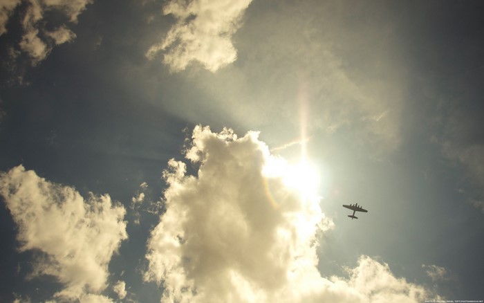 Airplane flying in the sky with clouds and sun