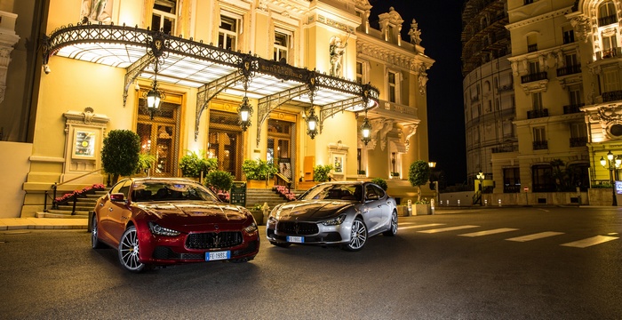 Two Maserati Ghibli cars parked in front of a building at night