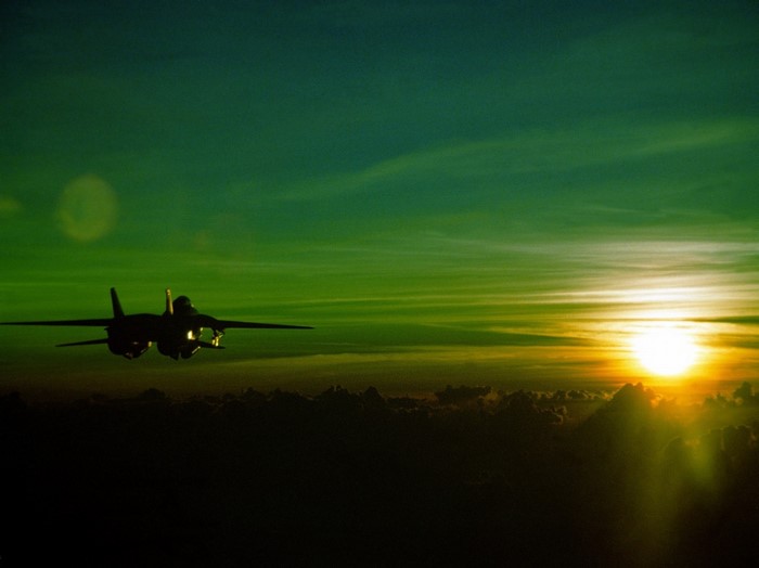 F-14 Tomcat flying at sunset over clouds