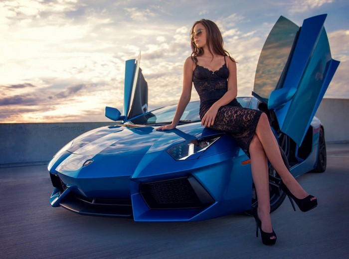 Woman in black dress sitting on a blue Lamborghini Aventador