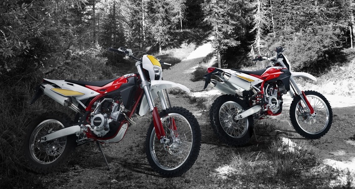 Two SWM RS 300 dirt bikes in a forest