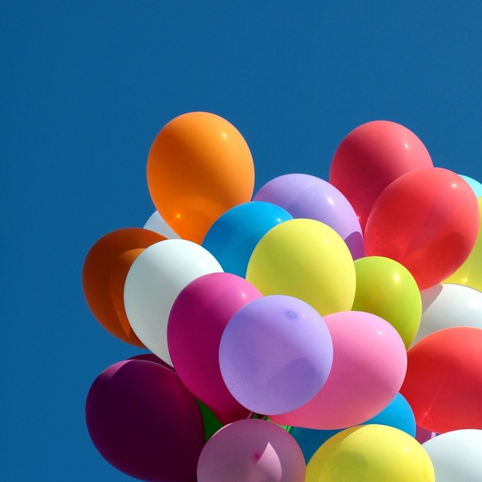 A collection of colorful balloons against a clear blue sky