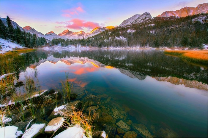 Snowy mountain lake reflection at sunrise