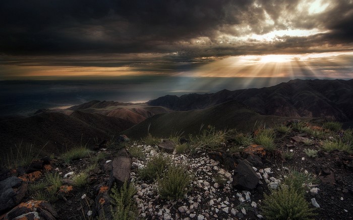 Sun rays over dark mountains at sunset