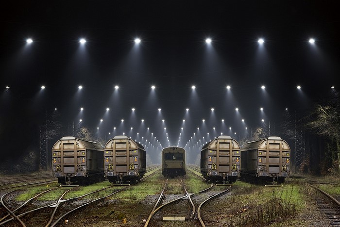 Freight trains lined up at night under stadium lights