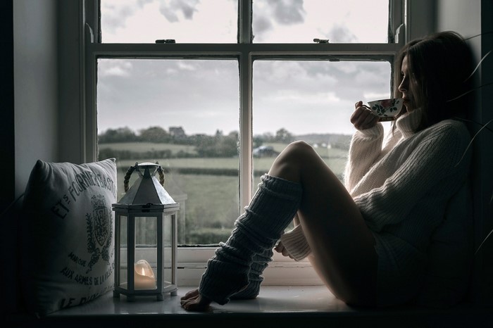 Woman drinking tea by the window