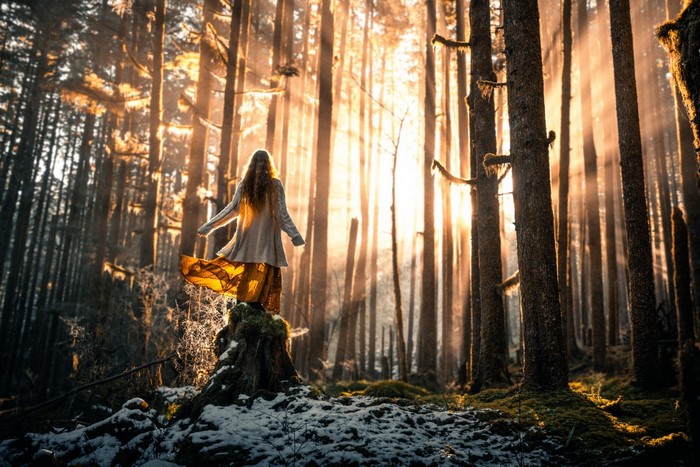 Woman in a forest with sunlight filtering through trees