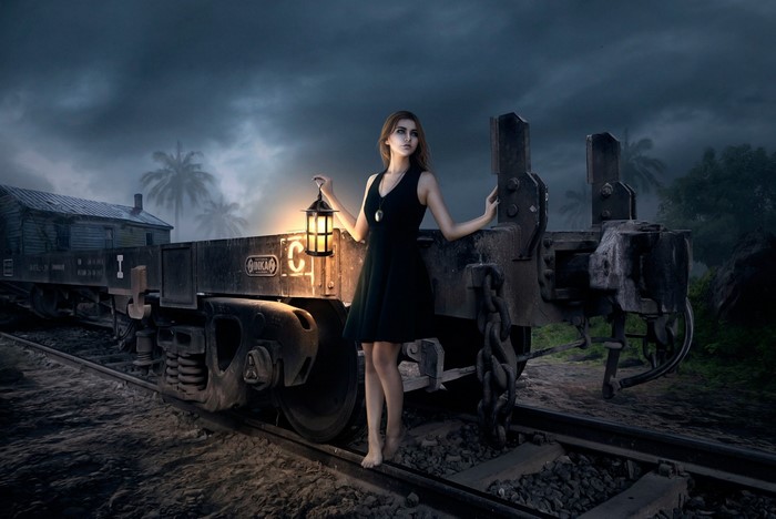 Woman with lantern on train tracks at night