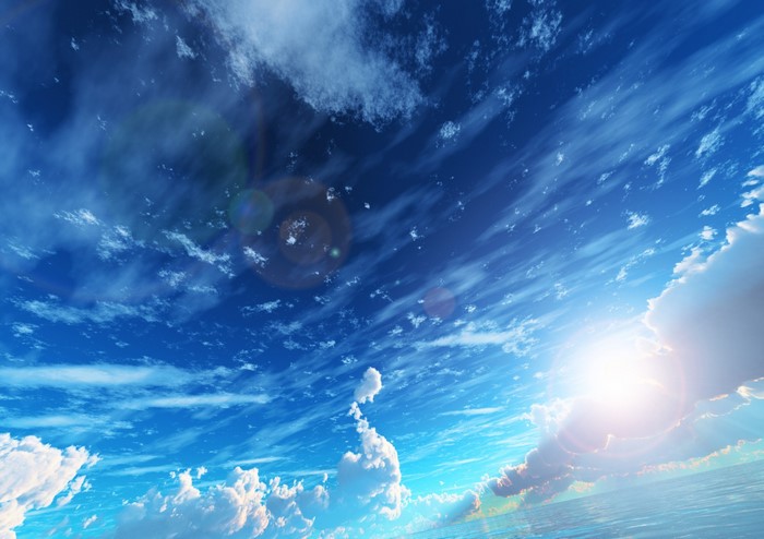 Blue sky with clouds and sun over the ocean