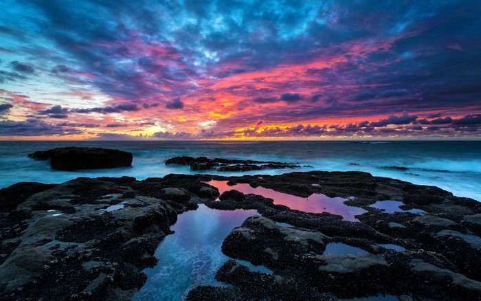 Sunset over the ocean with rocky shore