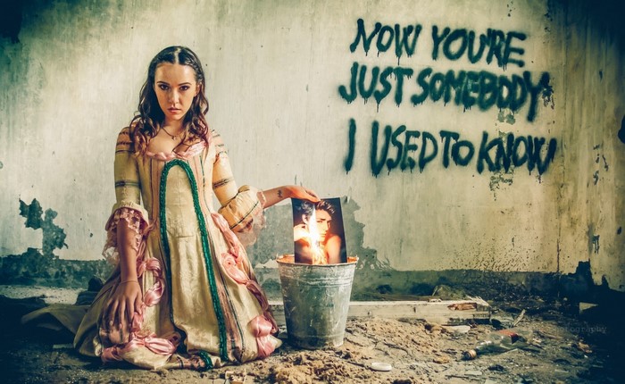 Woman in historical dress holding a burning photograph