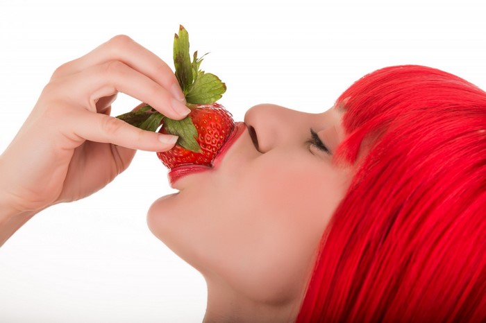 Woman with red hair eating a strawberry
