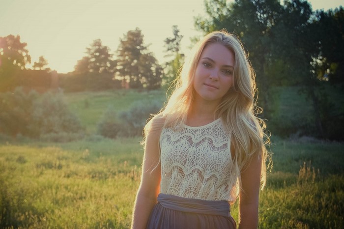 Young woman with blonde hair in a field at sunset