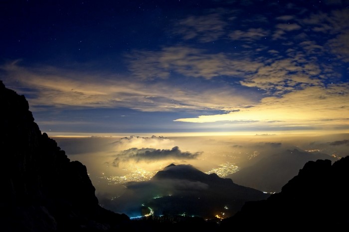 City lights at night from mountain peak with stars