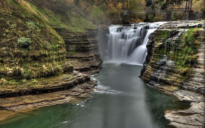Waterfall flowing over layered rocks in a gorge