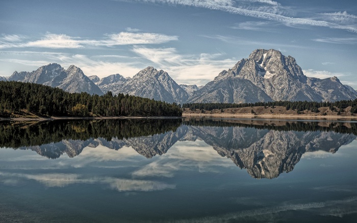 Mountains reflected in a calm lake with a forest