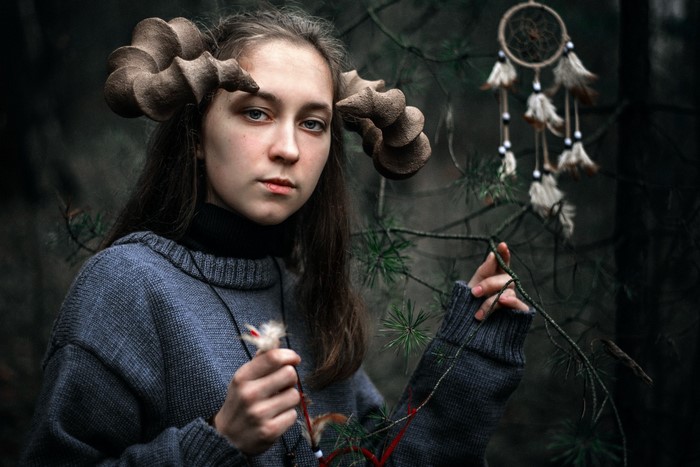 Woman with horns and dreamcatcher in forest