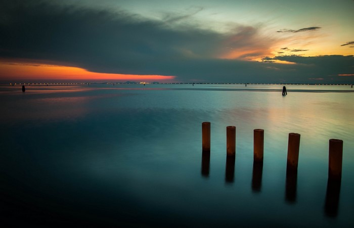 Sunset over the sea with wooden posts