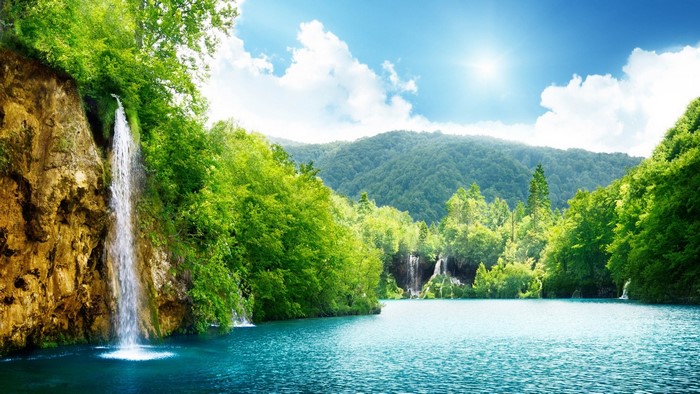 Waterfall cascading into a turquoise lake surrounded by green forest