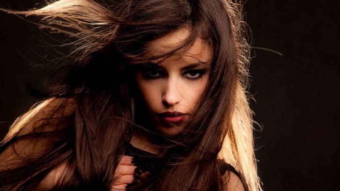 Woman with long brown hair and dark makeup