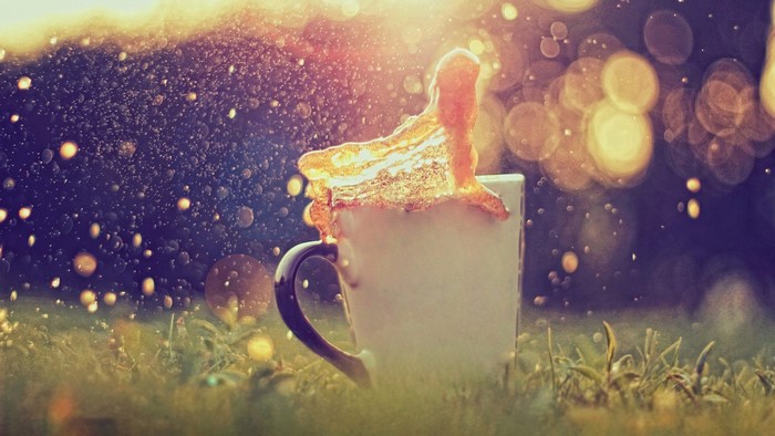 Coffee splash in a mug on grass with sunlight