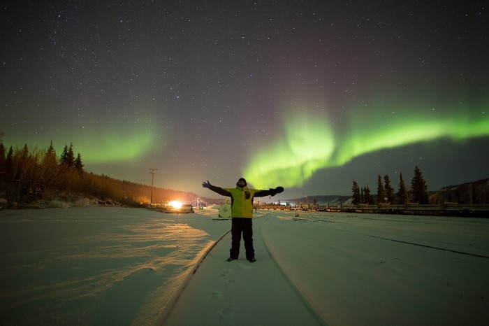 Man watching Aurora Borealis over snowy landscape