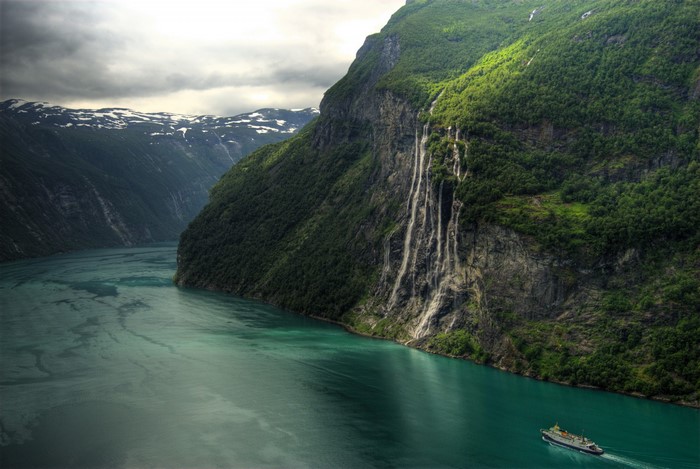Fjord landscape with Seven Sisters Waterfall and ship in Norway