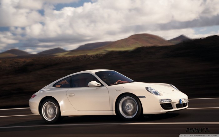 White Porsche 911 driving on a road with mountains
