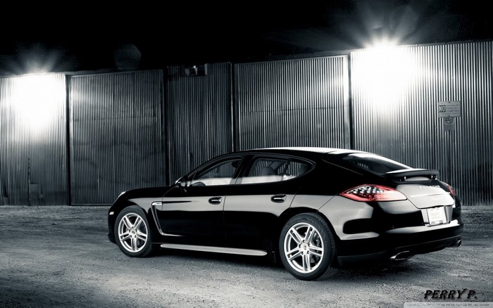 Black Porsche Panamera parked in front of corrugated metal doors
