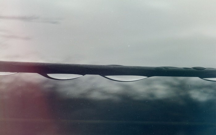 Water drops on a wire with cloudy sky reflection