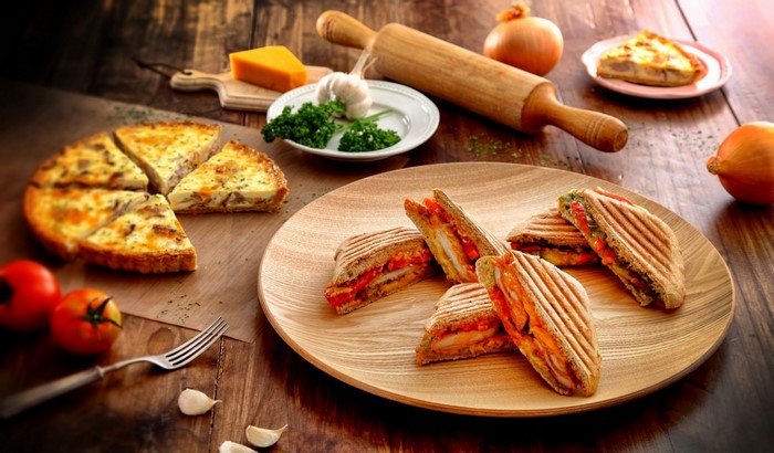 Grilled sandwiches and quiche on a wooden table