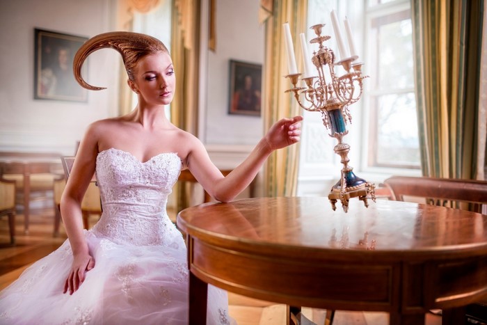 Woman in wedding dress with unique hairstyle near candelabra