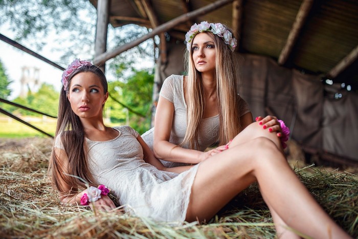 Two women in dresses with flower crowns in a barn