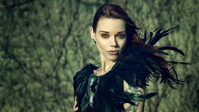 Woman with black feathers and skull necklace