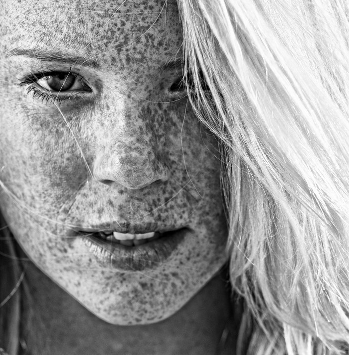 Close up black and white portrait of a girl with freckles
