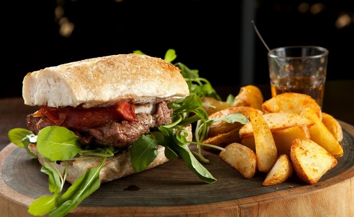 Steak sandwich with potato wedges and a drink