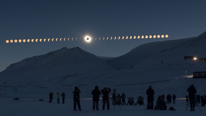 Solar Eclipse Over Snowy Mountains with Spectators