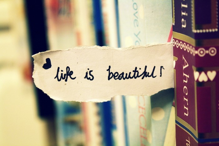 A torn piece of paper with "life is beautiful" written on it.