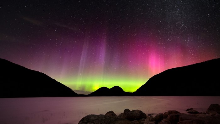Aurora Borealis over a lake and mountains at night