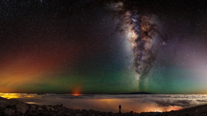 Man watches Milky Way and Aurora above clouds